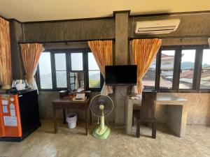 a room with a desk and a tv and windows at Baan Hom Muen Li in Mae Salong