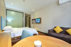 a hotel room with a bed and a couch and a table at JTOUR Inn Wuhan Changfeng Avenue Garden Expo in Wuhan