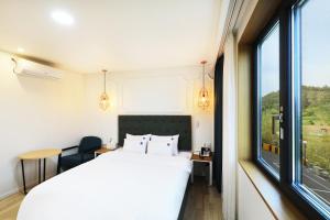 泗川Hotel Ryan的卧室里有一张白色的床和一扇大窗户