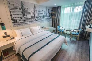 a bedroom with a large bed and a table and chairs at City Comfort Inn Shaoguan High-speed Railway Station Xilian Examination Center in Shaoguan