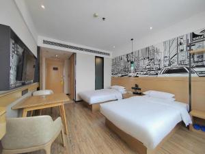 a bedroom with two beds and a desk and a tv at City Comfort Inn Xiaogan Xiaochang Bus Passenger Station in Xiaogan