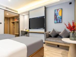 una camera da letto con un letto, un divano e una TV di Gya Hotel Wuxi Hubin Commercial Street Tai Lake Scenic Area a Wuxi
