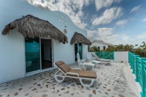 a patio with chairs and tables and a building at La Casa Del Velero, Beachfront in Chicxulub
