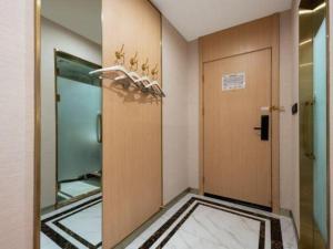 un couloir avec une porte et un miroir dans l'établissement VX Hotel Beijing Daxing Wufutang Metro Station Zhongke Dianshanggu, à Pékin