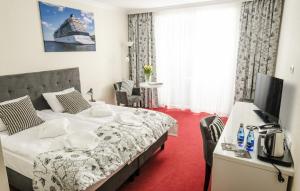 Pokój hotelowy z dużym łóżkiem i telewizorem w obiekcie Grand Kapitan Medi Spa - POKOJE OZONOWANE w mieście Ustronie Morskie +25 zdjęć