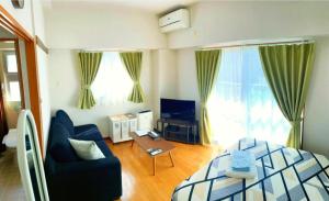 a living room with a blue couch and a bed at Anekkusu Nishihara intā mae in Naha