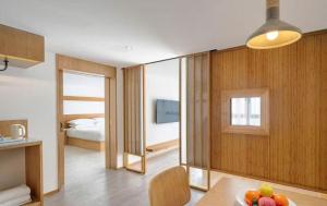 a living room with a table and a bedroom at Meijin All Suites Hotel Suzhou in Suzhou