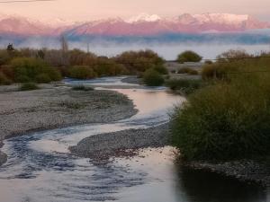 a river in the desert with mountains in the background at Atardecer en la Estepa in Dina Huapi