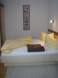 a white bed with yellow pillows and a purse on it at Apart Schultes in Pettneu am Arlberg