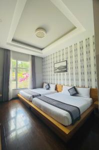 two beds sitting in a room with a window at Dalat Wind Hotel in Da Lat