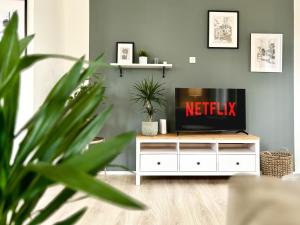 a living room with a tv on a white cabinet at COZEE - Spacious Apartment With Netflix in Kaiserslautern