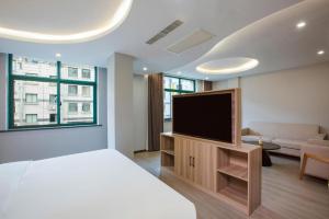 a bedroom with a bed and a flat screen tv at Borrman Hotel Jinhua Yiwu International Trade Mall in Yiwu