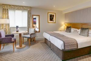 una camera d'albergo con letto, tavolo e sedie di Quy Mill Hotel & Spa, Cambridge a Cambridge