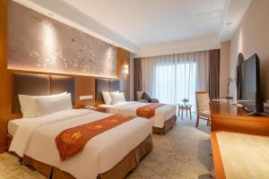 Una habitación de hotel con dos camas y un televisor. en Qingdao Blue Horizon Hotel Huangdao, en Huangdao