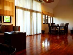 a living room with a wooden floor and a table and chairs at Baan Suan Nuan Ta in Samut Songkhram