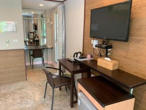 アムパワーにあるNopparat Garden Hotelの壁にテレビがかかっている机のある部屋