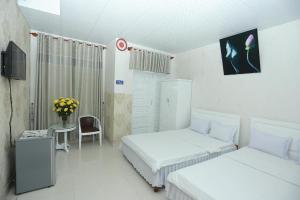 a room with two beds and a table and a tv at Thanh Long Hotel in Liên Trì (4)