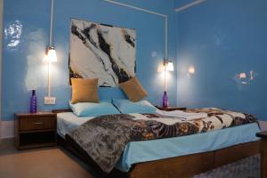 een slaapkamer met een groot bed met blauwe muren bij Tirthan Living Green Home Stays in Banjār
