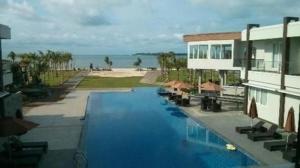 a swimming pool next to a building and the beach at D'Season Premiere Hotel in Kesembu