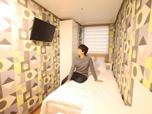ソウルにあるMyeongdong Mom Houseの部屋のベッドに座っている女性