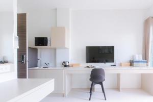 a white kitchen with a desk and a chair at Oh My Place in Chiang Rai