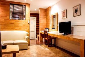 ein Zimmer mit einem Schreibtisch mit Fernseher und einer Couch in der Unterkunft The Bonanza Resort Khaoyai in Khanong Phra