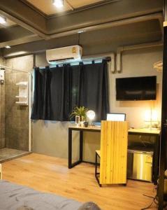 尖竹汶Poonpun Pet Friends Poshtel的房间里有一张桌子，房间里还有一扇窗帘。