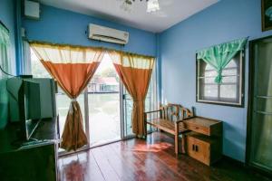une pièce avec des murs bleus, une télévision et une fenêtre dans l'établissement Raknatee Resort, à Ban Tha Chang (1)
