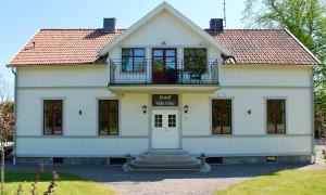 a white house with red windows and a balcony at Villa Göta in Forsvik
