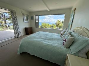 a bedroom with a bed and a large window at Luxury retreat overlooking Manly Beach in Whangaparaoa
