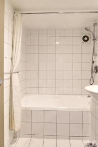a white tiled bathroom with a tub and a sink at Base Backpackers Queenstown in Queenstown