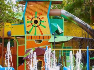 un parc aquatique coloré avec un toboggan et des fontaines dans l'établissement New Century Grand Hotel Xuzhou, à Xuzhou