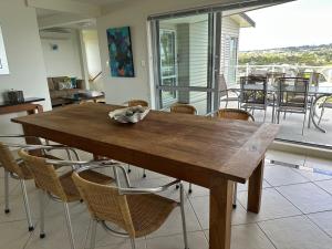 a wooden table and chairs in a room with a balcony at Luxury retreat overlooking Manly Beach in Whangaparaoa