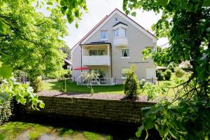 una casa bianca con un muro di mattoni e alberi di Haus am Mühlenweg - modern und lichtdurchflutet a Bad Wörishofen