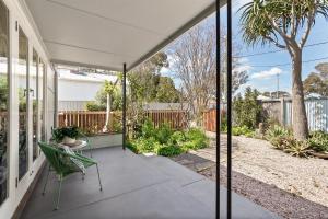 a patio with a green chair under a white umbrella at Elva Garden Cottage in Margaret River Town +15 photos