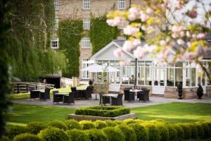 a garden with tables and chairs and a building at Quy Mill Hotel & Spa, Cambridge in Cambridge