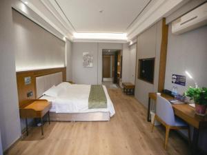 a bedroom with a bed and a desk and a television at GreenTree Inn Jiuquan Century Plaza Hotel in Jiuquan