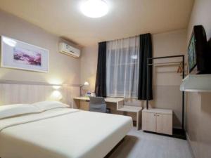 a bedroom with a bed and a desk and a window at Jinjiang Inn Taiyuan Longtan Park in Taiyuan