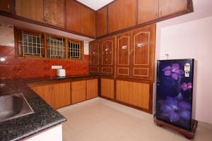 a kitchen with wooden cabinets and a refrigerator with flowers on it at AAHA Serenity Stays in Puducherry