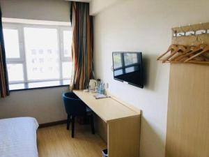 a room with a desk and a tv on a wall at 7 Days Inn Korla Passenger Station in Korla +56 photos