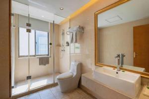 une salle de bain avec un lavabo, une douche et un miroir dans l'établissement Vienna International Hotel Lhasa Potala Palace, à Lhasa 224 autres photos