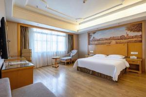 a hotel room with a bed and a large painting on the wall at Vienna International Hotel Lhasa Potala Palace in Lhasa