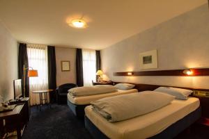 a hotel room with three beds and a television at STADT-Hotel Lörrach GbR in Lörrach