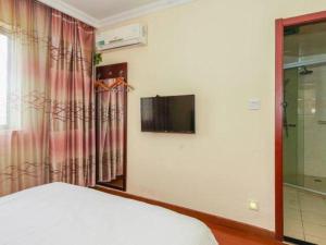 une chambre avec un lit et une télévision sur un mur dans l'établissement GreenTree Inn Suzhou Wujiang Zhenze Town Zhennan Road Express Hotel, à Suzhou