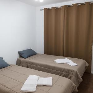 two beds in a room with curtains and towels on them at Charme da Serra Ape Aconchegante em Correas in Petrópolis