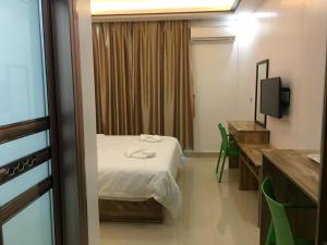 a room with a bed and a desk and a television at Hotel Primera in Zamboanga