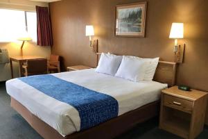 a hotel room with a large bed with a blue blanket at Travelodge by Wyndham Powell in Powell
