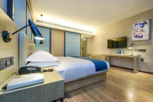 - une chambre avec un lit et un bureau avec un téléphone dans l'établissement Echarm Hotel Guiyang International Convention & Exhibition Center, à Guiyang