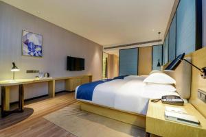 a bedroom with a bed and a desk and a television at Echarm Hotel Guiyang International Convention & Exhibition Center in Guiyang +221 photos