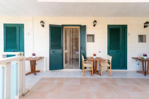 a patio with green doors and a table and chairs at Atenaion Otranto in Otranto +38 photos